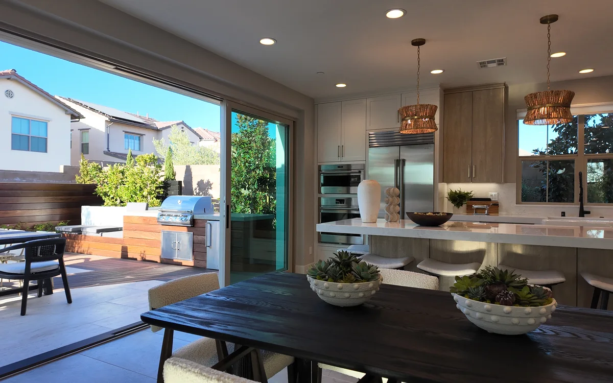 Kitchen and dining opening to a deck and outdoor kitchen through a full-width slider — NHG HOME project, Orange County